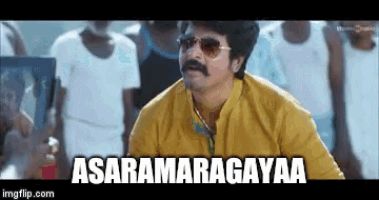 a man wearing sunglasses and a yellow shirt is standing in front of a crowd and says asaramagayaa