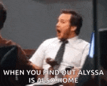 a man in a suit and tie is talking to another man while holding a remote control .