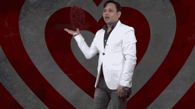 a man in a white suit is holding a heart in his hand