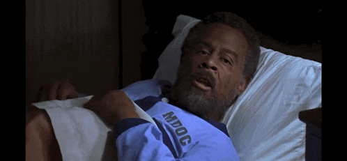 a man is laying in a hospital bed wearing a shirt that says mdcc