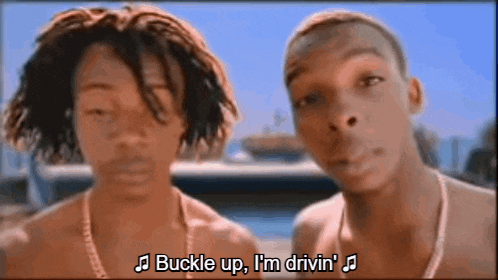two men are standing next to each other and one of them says " buckle up i 'm drivin "