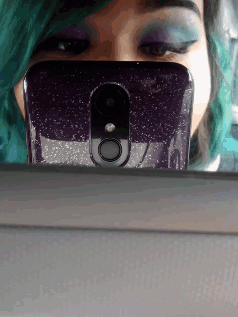 a woman with green hair takes a picture of herself in a mirror