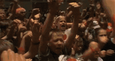 a crowd of people with their arms in the air and a sign that says ' a ' on it
