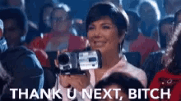 a woman is holding a video camera in a crowd and says " thank u next bitch "