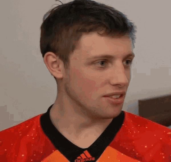 a man wearing a red adidas shirt looks to the side