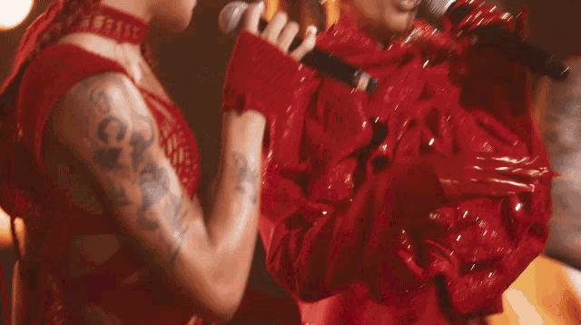 two women singing into microphones with one wearing a red outfit