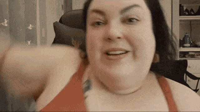 a woman in a red bra is sitting in a chair with her arm outstretched and smiling .