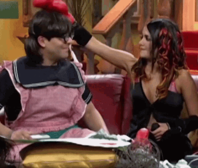 a woman is touching a man 's head with a red glove