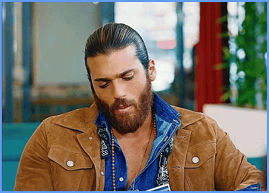 a man with a beard wearing a brown jacket and a blue shirt