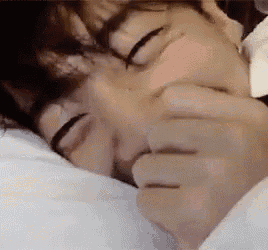 a close up of a person sleeping on a bed with their hands on their face .