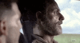 a man with a beard is sitting in the back seat of a car with another man .