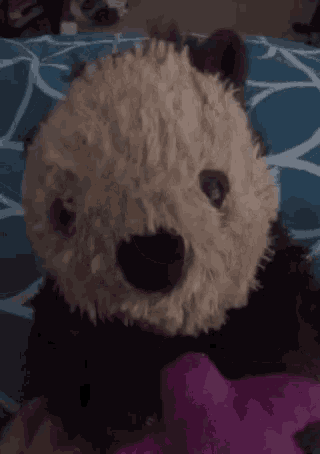 a teddy bear is laying on a bed next to a pink stuffed animal .