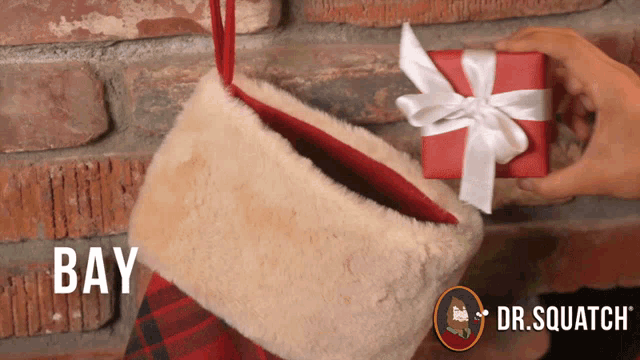 a person is putting a gift in a santa stocking with the word bay on it