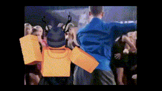 a man in a blue shirt is dancing in front of a crowd of people in a room .