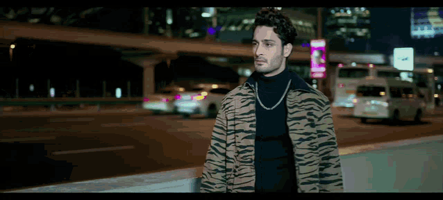 a man wearing a zebra print jacket and a black turtleneck is walking down a street at night
