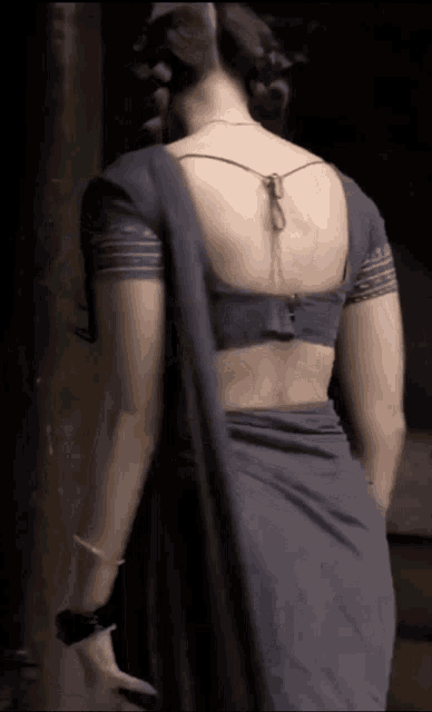 the back of a woman wearing a gray blouse and a black saree .