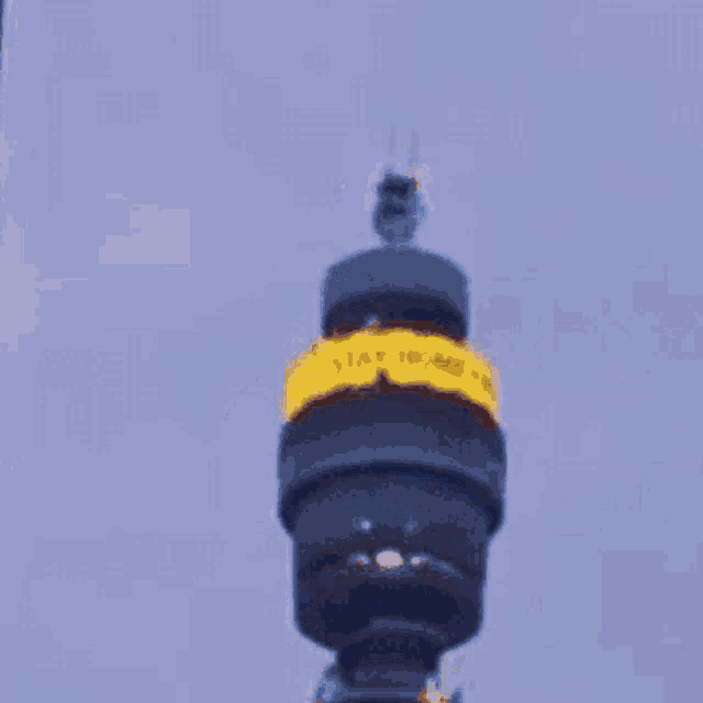 a very tall tower with a yellow sticker on it that says " i am who "
