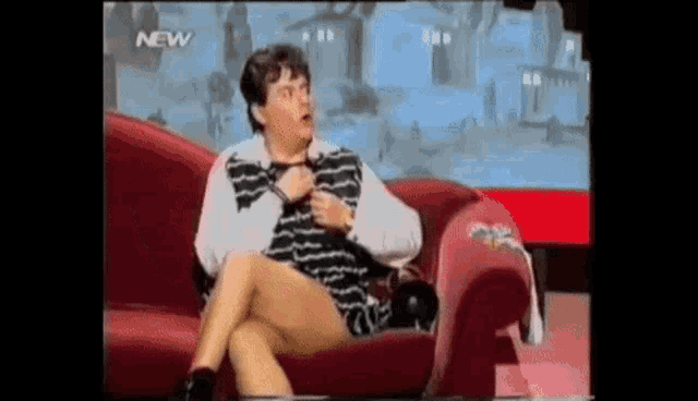a woman is sitting on a couch with her legs crossed in front of a new sign .
