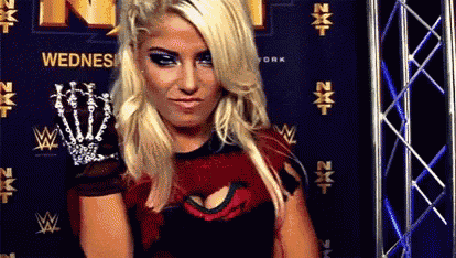 a blonde woman in a red and black dress is standing in front of a sign .