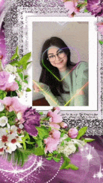 a picture of a woman in a green sweater and glasses is surrounded by purple flowers