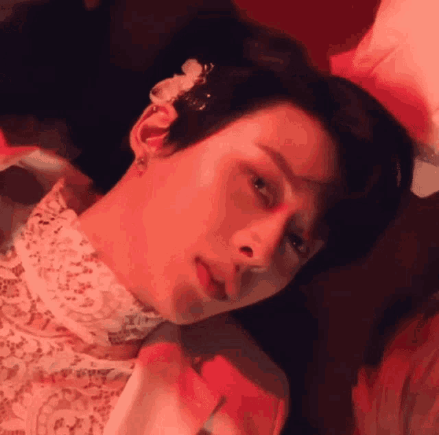 a close up of a person laying down with a flower in their hair