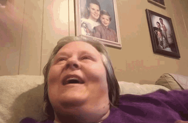 a woman sitting on a couch with a picture of a family behind her
