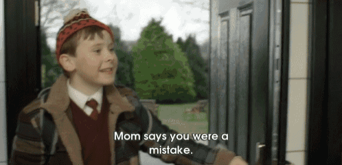a young boy is standing in front of a door and saying mom says you were a mistake