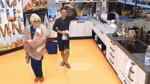 a man and a woman are dancing in a kitchen while wearing sunglasses .