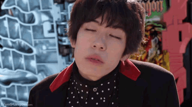 a young man with his eyes closed is wearing a polka dot shirt and a black jacket ..