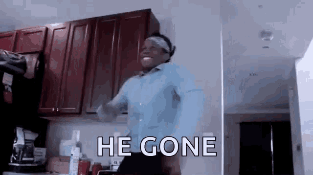 a man is dancing in a kitchen with the words `` he gone '' written on the wall .