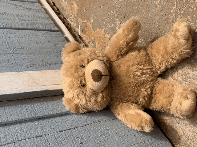 a teddy bear is laying on its back on a wooden floor