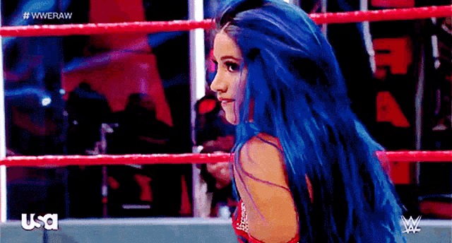 a woman with blue hair is standing in a wrestling ring with usa written on the bottom