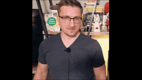 a man wearing glasses stands in front of a shelf full of books and a sign that says " home modern eastern "
