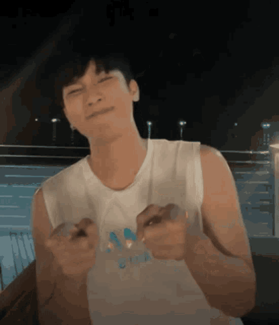 a man wearing a white adidas tank top is making a funny face