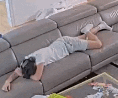 a man is laying on a couch in a living room with a headset on .