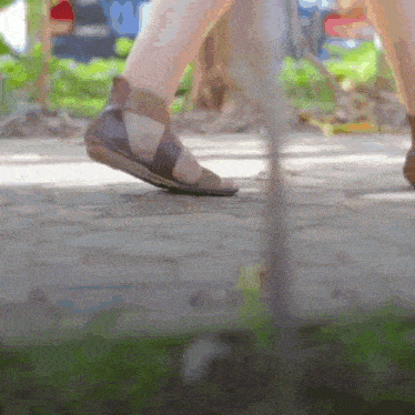 a person wearing sandals walks on a sidewalk