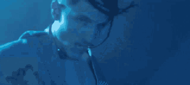 a man with dreadlocks and a choker is standing in a dark room .