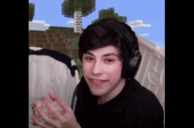a young man wearing headphones and a black shirt is holding a piece of ice in his hands .