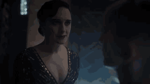 a woman in a black sequined dress looks at a man