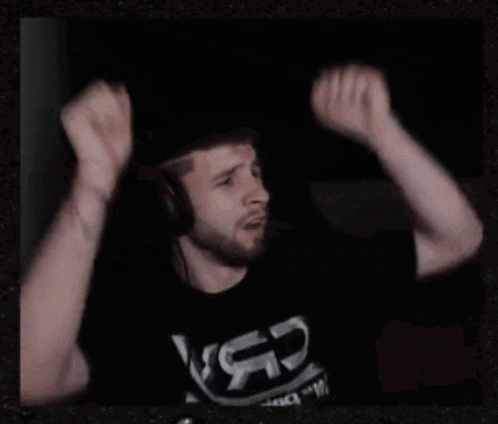 a man with a beard is raising his arms in the air while wearing a black shirt that says lsg