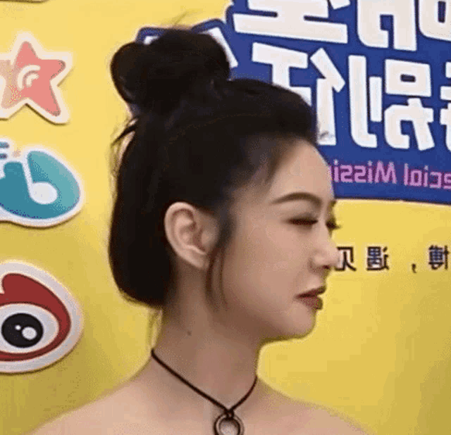 a close up of a woman 's face with a bun in her hair .