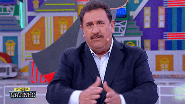 a man in a suit is standing in front of a sign that says programa ratinho