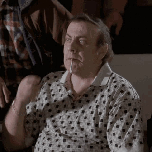 a man with a cigarette in his mouth wearing a plaid shirt