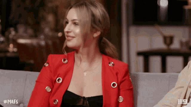 a woman in a red jacket sits on a couch with the hashtag # mafs