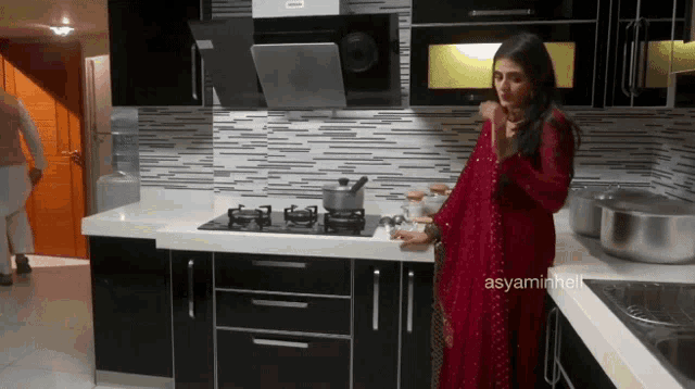 a woman in a red dress is standing in a kitchen with the hashtag asyaminheli
