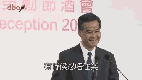 a man in a suit and tie is standing in front of a microphone in front of a sign that says reception 20 .
