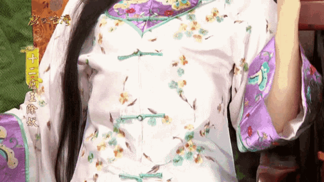 a woman wearing a white and purple floral shirt with chinese writing on it