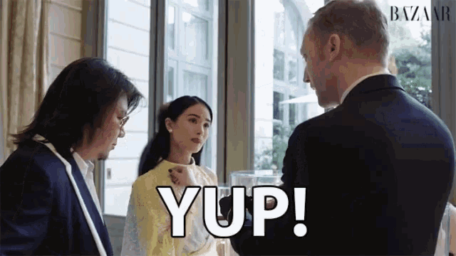 a man in a suit is talking to a woman in a yellow dress and the word yup is on the bottom