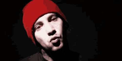 a close up of a man wearing a red beanie with red eyes .