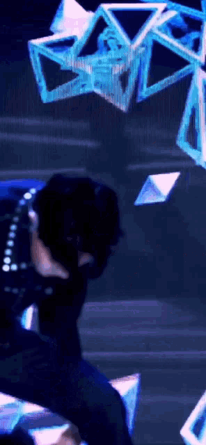 a man in a black suit is dancing in front of a blue background